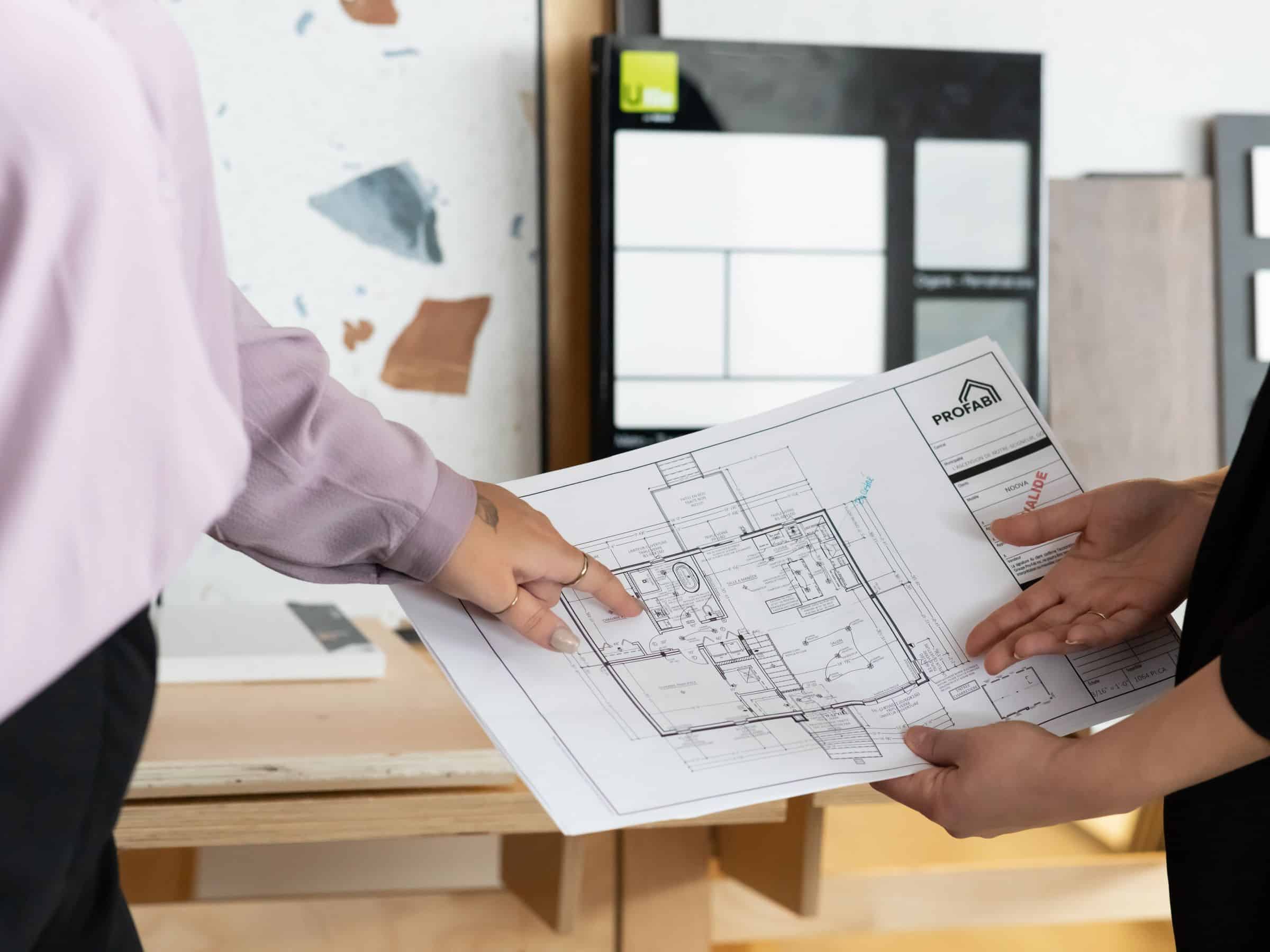 Two persons holding a house plan.