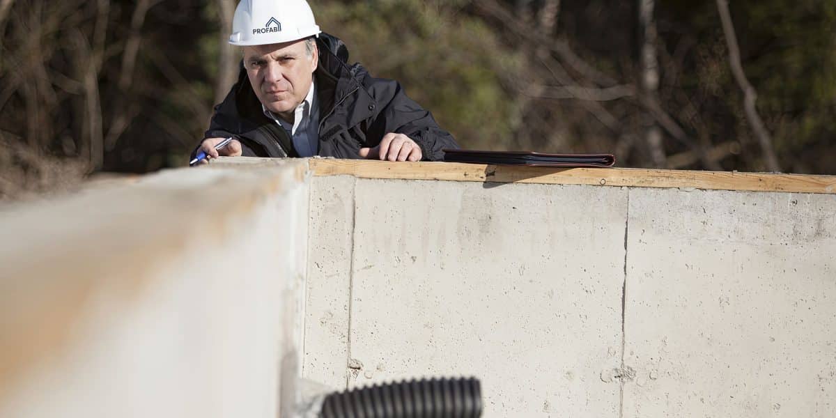 Inspecteur évaluant les fondations de la maison préfabriquée.