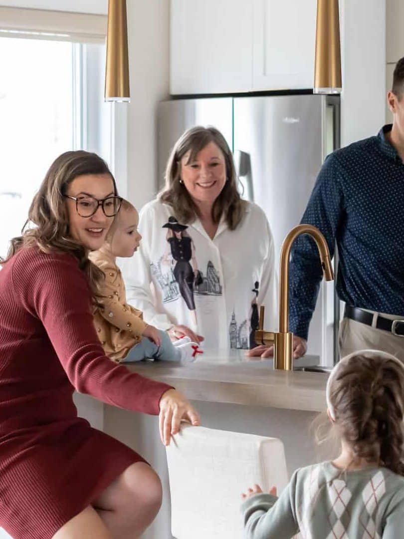 Mother with a baby accompanied by grandmother and another child around a kitchen's table.