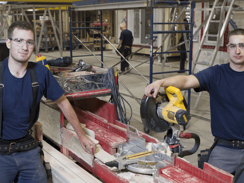 Hommes en usine travaillant sur la construction d'une maison préfabriquée.