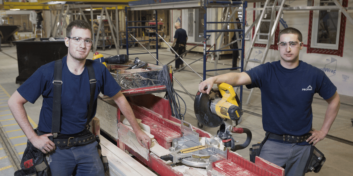 Hommes en usine travaillant sur la construction d'une maison préfabriquée.