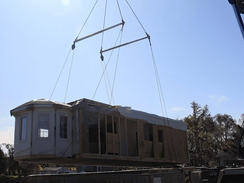 Crane depositing pieces of a prefabricated house upon delivery.