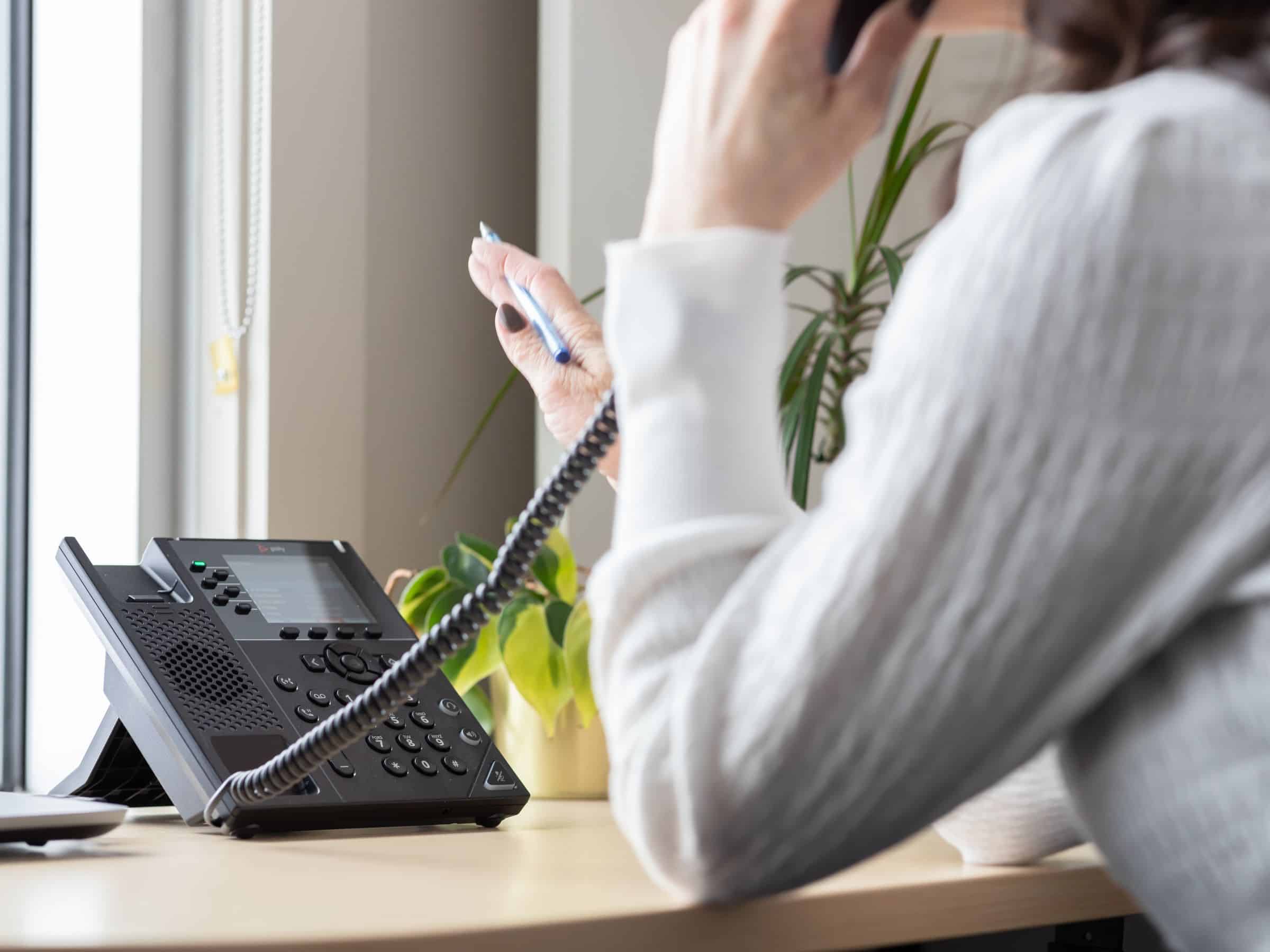 Woman seen from behind talking on the phone about her aftersales warranty.