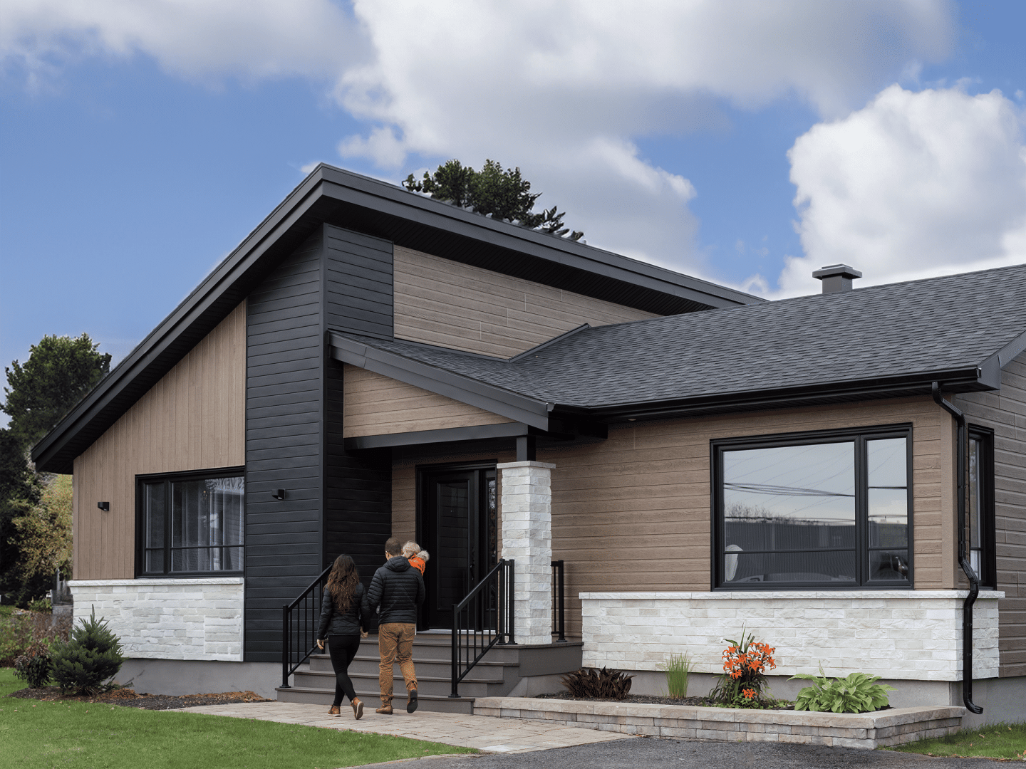 Prefabricated single storey of the Tryka model in contemporary style. Front exterior view. A couple heading to the entrance.