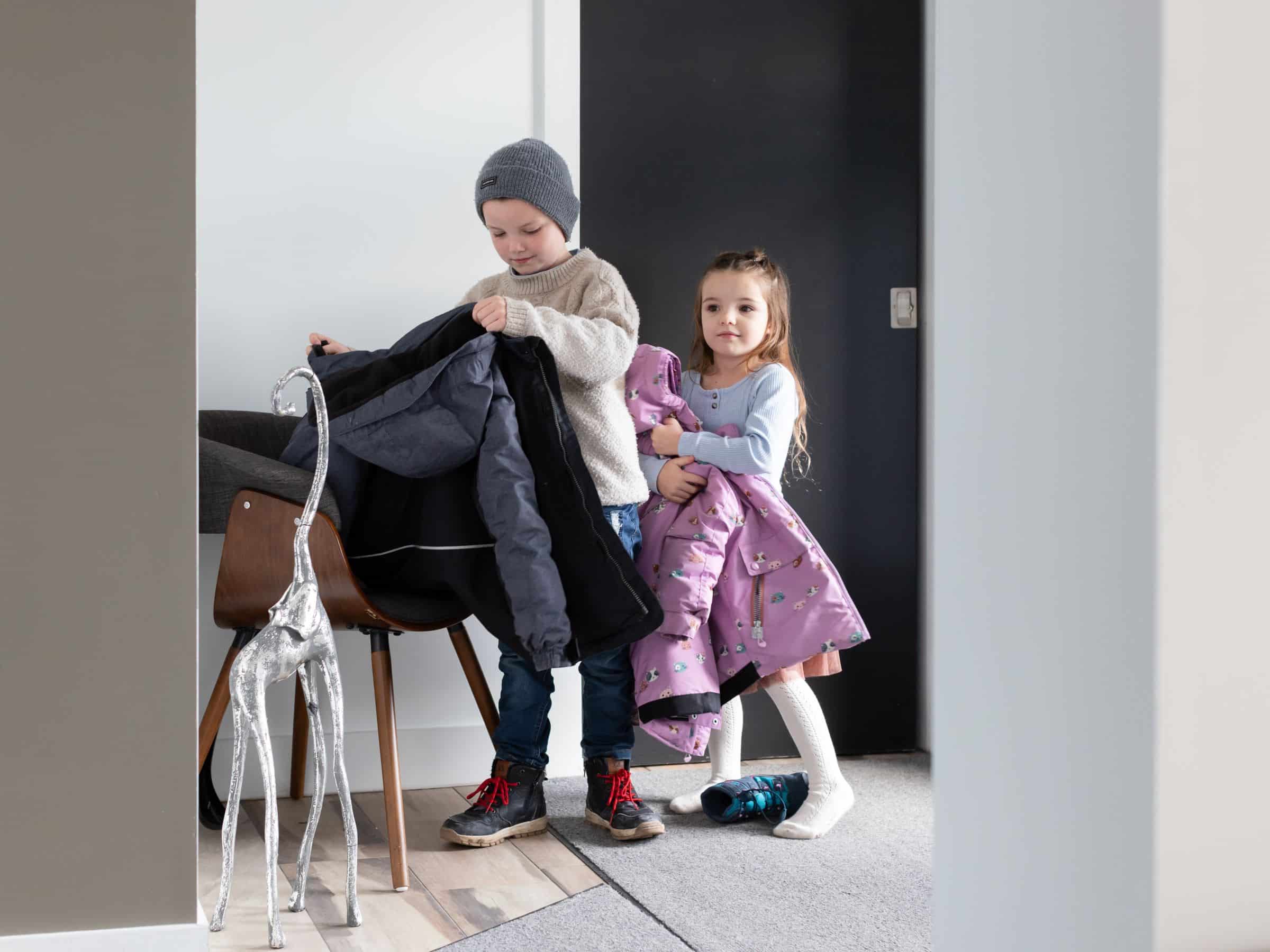 Two children ready to leave in the hallway.