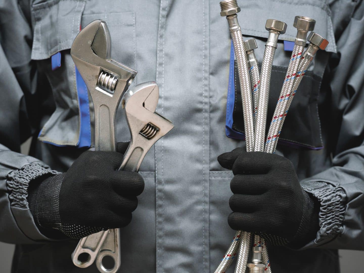 Plombier travaillant et qui tient ses outils dans ses mains.
