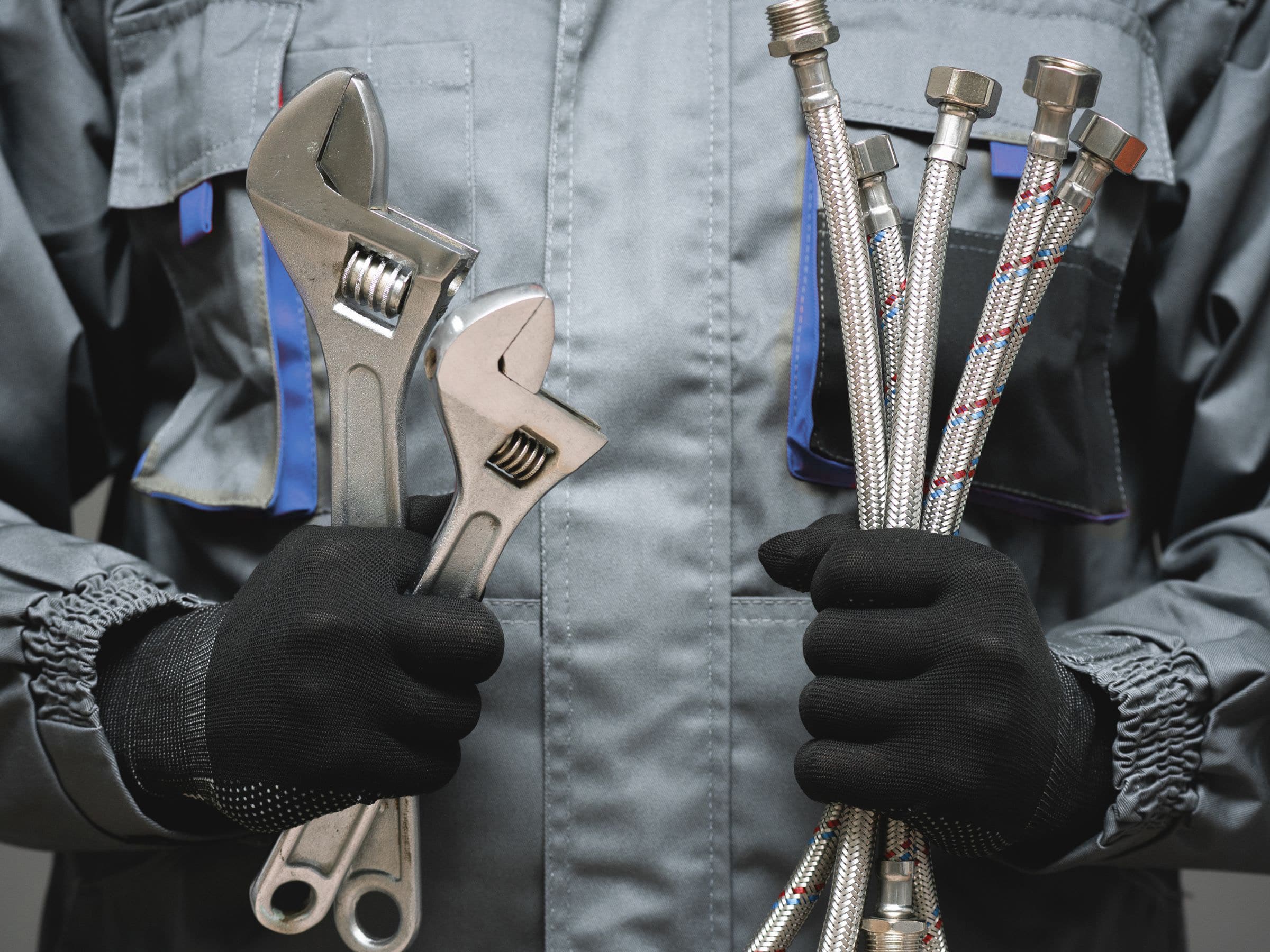 Plombier travaillant et qui tient ses outils dans ses mains.