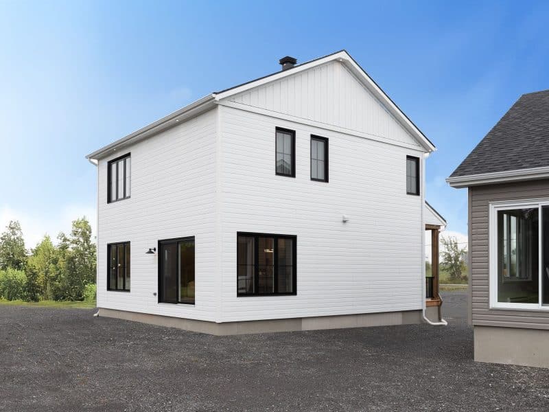 Modèle Edena, une maison usinée à deux étages au style farmhouse moderne et spacieuse. Vu de l'exterieur arriere.